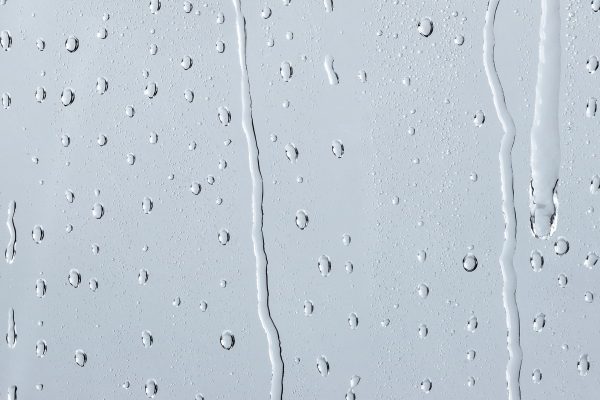 Condensation running down a window pane — surface condensation forms where warm, humid indoor air meets a cold surface
