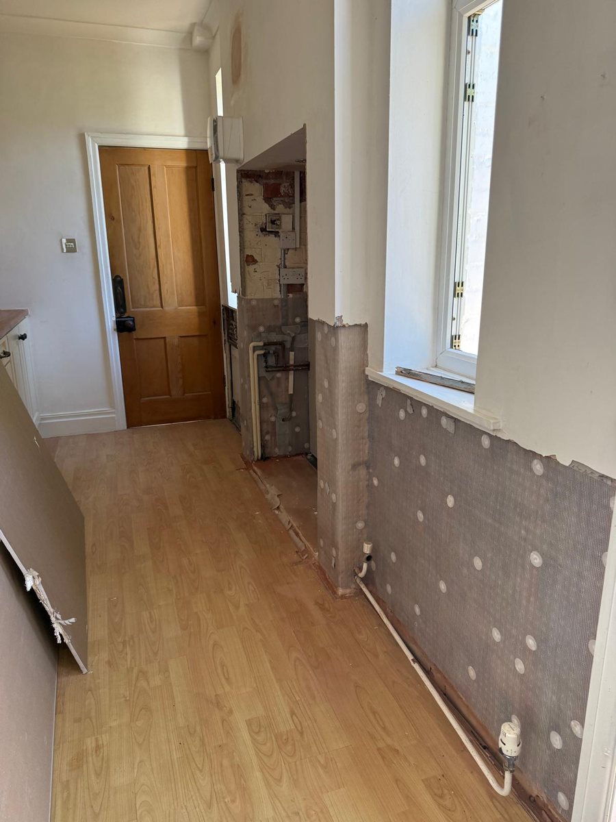 Hallway mid-treatment: plaster stripped to a metre, DPC injected, mesh-faced membrane fitted